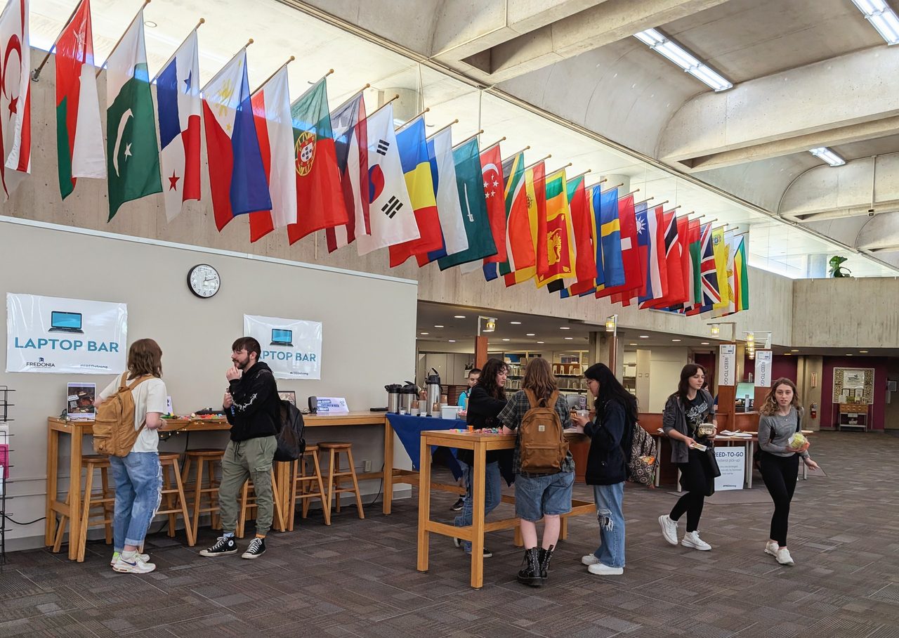 Students lined up at the Fuel Up laptop bar beneath the flags